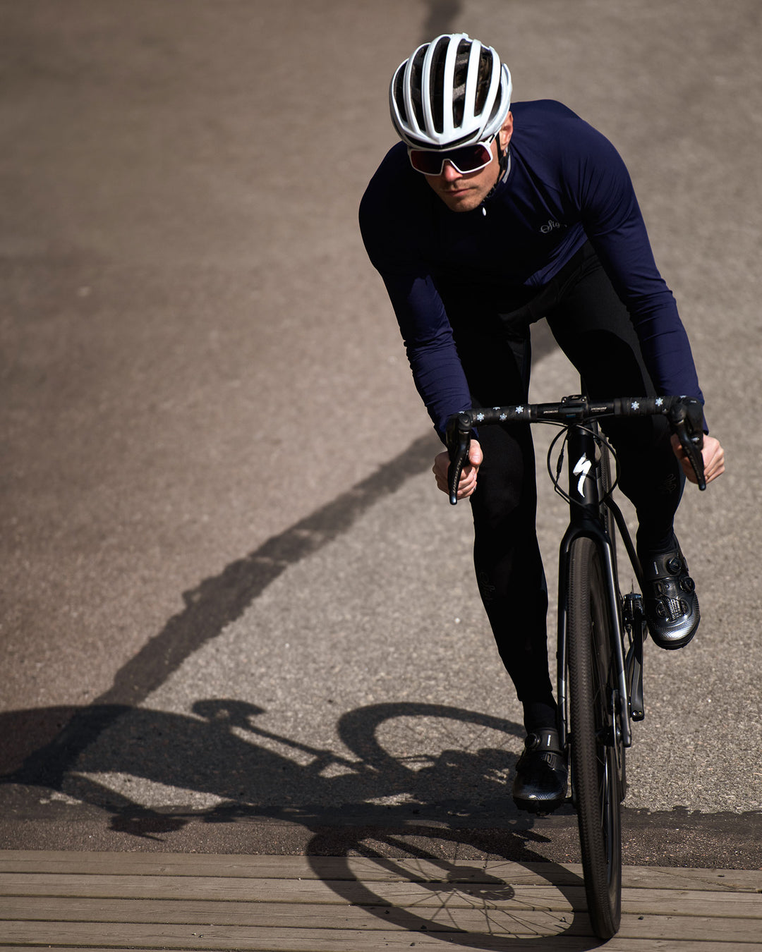 Road cyclist wearing a dark blue long sleeved cycling jersey by Sigr